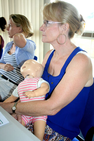 A grandmother listens to the correct treatment for a choking baby before practicing on a mannequin. (Pic: Rosie Wang)
